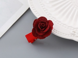 Detail of red rose hair clip with shimmering fabric petals and ribbed duckbill base