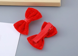 Detail view of red velvet bow hair clips with gold sparkles and metal alligator clips