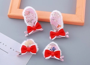 Détail de pinces à cheveux oreilles de lapin en peluche rose avec nœuds rouges