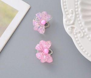 Detailed view of pink resin glitter bow ear clips with metal backings and pearls