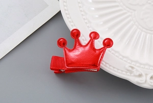 Detail of red festive crown hair clip with metallic finish and ribbon wrapped duckbill clip