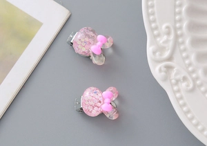 Close-up of glittery resin cartoon clips for girls with pink and purple sequins