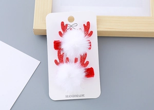 Détail de pinces à cheveux cornes de renne à paillettes rouges avec pompons en peluche blanche