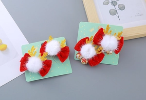 Détail de pinces à cheveux bois de renne avec nœuds rouges, cloches et pompons blancs