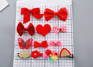 Flat lay of 12-piece red bow hair clip set with sequins and fur balls for kids