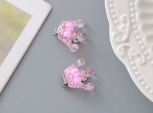 Detail of pink resin crown hair clips with glitter sequins and bow on grey background