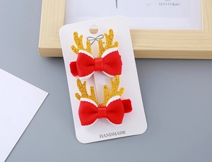 Détail de pinces à cheveux nœuds rouges festifs avec bois de renne dorés pailletés sur carte