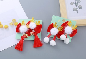 Détail de pinces à cheveux avec nœuds en velours rouge, bois dorés et pompons blancs