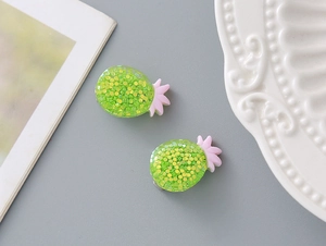 Close-up of cute resin pineapple ear clips with colorful glitter for young girls