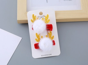 Détail de pinces à cheveux de Noël avec bois dorés, pompons blancs et nœuds rouges