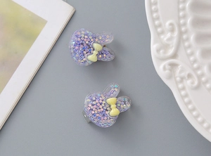 Detail shot of cute purple resin rabbit ear clips with glitter and yellow bows