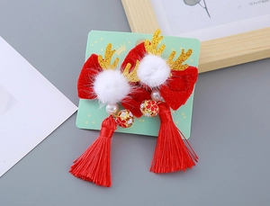 Détail de pince à cheveux avec nœud rouge, bois dorés, cloches et longs pompons