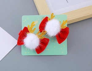 Détail de barrettes à nœud en velours rouge avec bois de renne dorés et pompons blancs