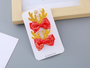 Détail de barrettes nœuds rouges faits main avec bois de renne dorés pour fille