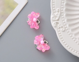 Detailed view of pink glitter resin bow ear clips for girls with comfortable silver metal back