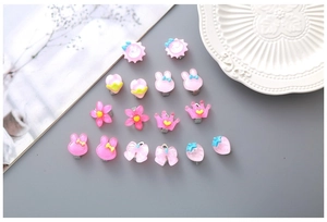 Vue détaillée des boucles d'oreilles clips en résine rose aux formes d'animaux et fleurs
