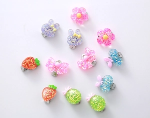 Flat lay of 11-piece resin kids clip-on earrings set with glitter cartoon shapes