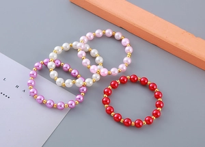 Detail of four-piece children's pearl bracelets with colorful beads and golden spacers