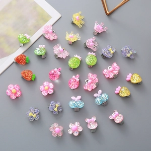Glittery resin ear clips for girls with cute crown flower shapes on dark background