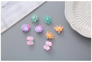 Vue détaillée de clips d'oreilles fleurs et couronnes en résine colorée pour petites filles
