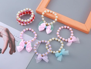 Detail view of five girls beaded bracelets with pearls and colorful fabric bows