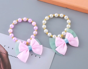 Detail shot of kids pearl bracelets with pink satin and green mesh bows on flat lay