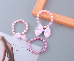 Detail of beaded children's bracelet set with pearls, gold beads, and fabric bows