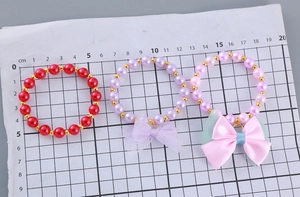 Close-up of three girls' pearl bracelets featuring colorful satin and mesh bows