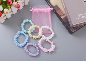Flachbild von bunten Organza-Haargummis in sechs Farben mit einem rosa Geschenkbeutel