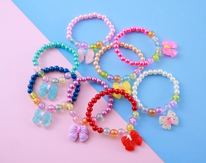 Flat lay of colorful children's beaded bracelets with cute resin bow and butterfly charms