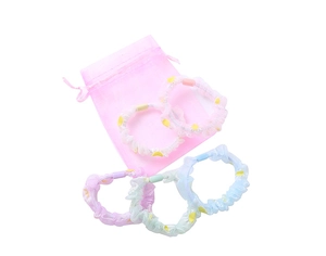Nahaufnahme von fünf farbenfrohen Organza-Haargummis mit Blumendruck in einer Geschenktüte