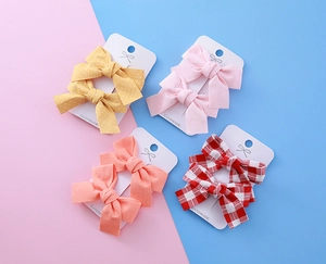 Détail de barrettes à nœuds faites main avec motifs à pois, vichy et couleurs unies