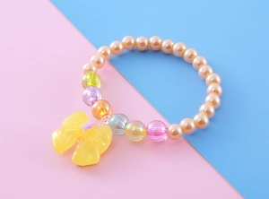 Close-up of kids beaded bracelet with colorful imitation pearls and yellow resin bow charm