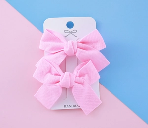 Détail de barrettes nœuds en tissu rose faites à la main pour filles sur carte blanche