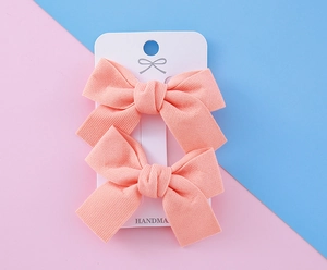 Gros plan de barrettes à nœuds roses faits main pour filles sur une carte blanche