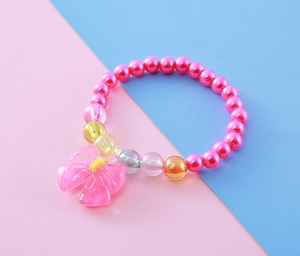 Close-up of kids' beaded bracelet with pink faux pearls and resin bow charm detail