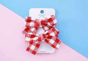 Détail de barrettes à cheveux à carreaux vichy rouge et blanc sur carte blanche