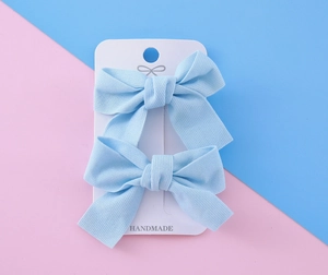 Détail de barrettes à cheveux nœud bleu clair fait main sur emballage carton blanc