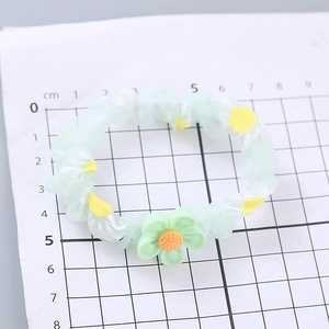 Hellgrüner Organza-Haargummi mit Gänseblümchen-Print und Blumenanhänger auf Maßbrett