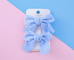 Détail de barrettes à nœud vichy bleu fait main sur une carte de présentation rose