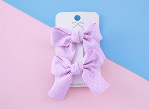 Détail de pinces à cheveux noeud violet à pois pour filles sur une carte