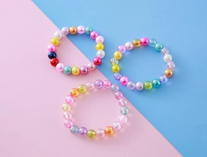 Détail de trois bracelets de perles colorées aux tons pastel avec des pendentifs mignons