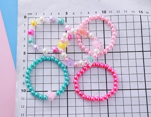 Vue détaillée de bracelets de perles colorées pour filles avec breloques papillon sur règle