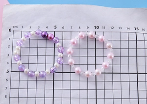 Détail de bracelets en perles colorées avec pendentifs mesurés sur une grille graduée cm