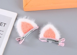 Detail view of plush pink and white cat ear hair clips with ribbon wrapped metal base