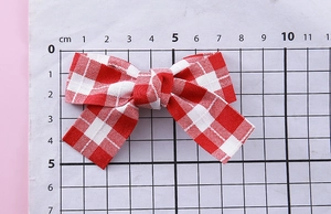 Détail de la barrette nœud à carreaux rouges et blancs avec mesure de 9cm sur règle