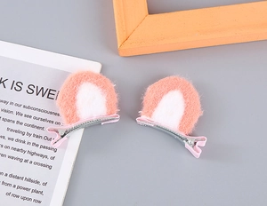 Detailed view of pink and white plush cat ear hair clips with fabric-wrapped metal duckbill clips