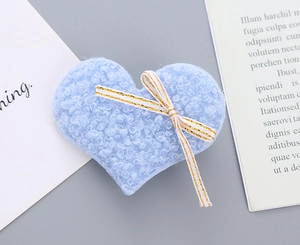 Detailed close-up of a blue fuzzy heart hair clip with a stylish gold-striped bow tie