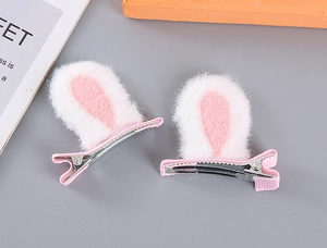 Detail of plush pink and white rabbit ear hair clips with fabric-covered metal alligator clips