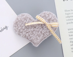 Close-up of soft grey faux fur heart hair clip with elegant gold-edged white ribbon bow